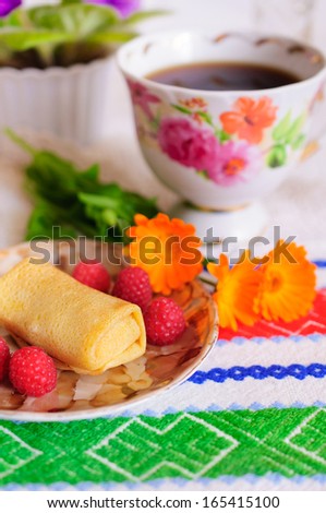 Pancakes with filling. Decorated with raspberry and orange flowers.