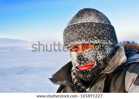 Portrait of a man in a cap and a ski mask. Winter in frost.