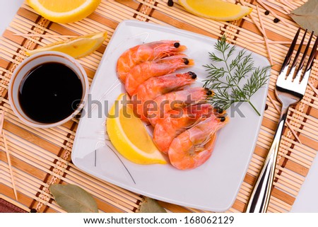 Boiled shrimp on a square plate. Decorated with a sprig of dill.