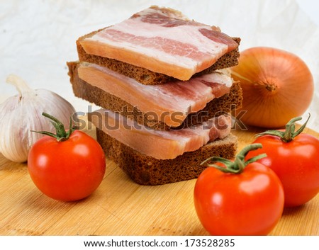 Of salted bacon sandwiches on rye bread. With cherry tomatoes and garlic.