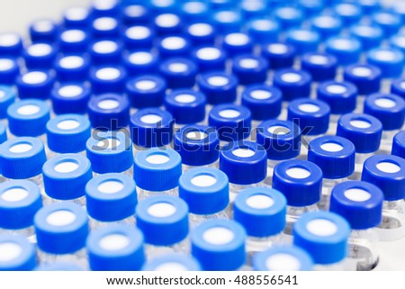 Rows of glass vials in the tray automatic liquid dispenser. Laboratory chemical equipments. Shallow depth of field