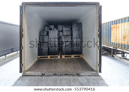 Road freight trailer loaded with boxes. Boxes wrapped in a black stretch film. Interior view of empty semi truck lorry
