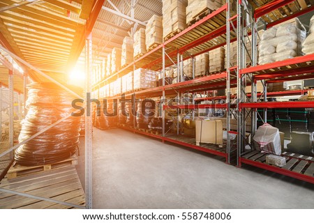 Warehouse industrial and logistics companies. Commercial warehouse. Boxes and crates stocked on the shelves of three storey. Bright sunlight.