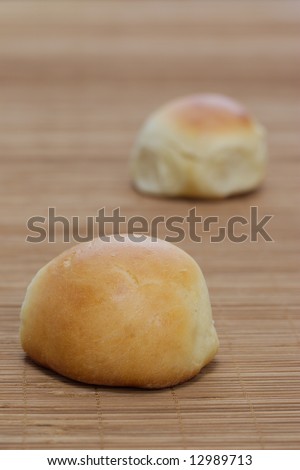 Two fresh bread rolls on a brown bamboo table mat.