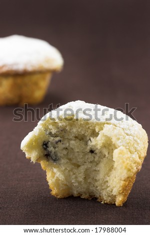 Freshly baked mini blueberry muffins on a brown cloth background.
