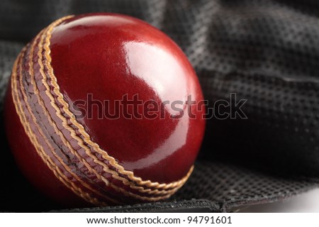 A shiny, new test match cricket ball in a wicket keeping glove.