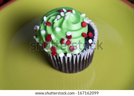 Shot of a mini cupcake on a green plate.