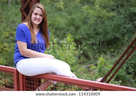 Young woman sitting on the edge of an old rusted bridge in Columbia, Missouri