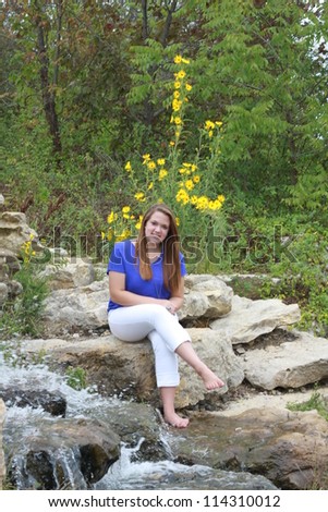 Young woman sitting near rushing water attraction at Stephen\'s Lake Park in Columbia, Missouri