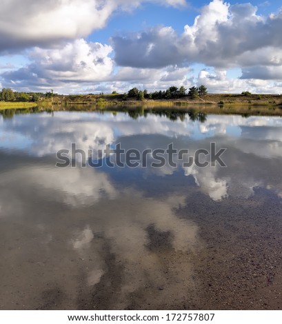Tranquil morning near a lake. Reflection of the clouds in lake water