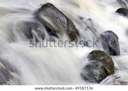 Forest waterfall in spring, strong streams of water fight about stones