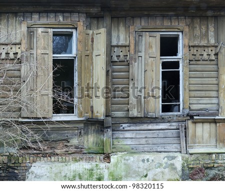 Old broken house in spring, damaged windows and sun-blinds