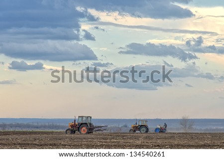 Spring field work. Farmers on tractors working in the fields, plowing and sowing.