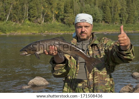 Fisherman holding a big fish salmon. Much luck. Self portrait