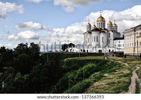 Assumption Cathedral at Vladimir in summer, Russia. One of the Famous spot during the sightseeing Golden Ring Tour. Green grass and trees at the background. Blue sky with clouds.