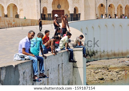 CASABLANCA, MOROCCO - AUGUST 18: Local people sitting at the pavement in front of King Hassan II Mosque on August 18, 2011 in Casablanca, Morocco. It is the largest Mosque in the country