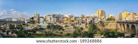 Panorama of Color Painted Houses hanging over the dried river in Villajoyosa, Alicante, Spain. Two bridges on the side.