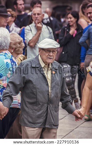 BARCELONA, SPAIN - SEPTEMBER 15, 2013: Close view of people (seniors) holding hands and dancing Sardana at Plaza Nova. The dance is a type of circle dance typical of Catalonia.