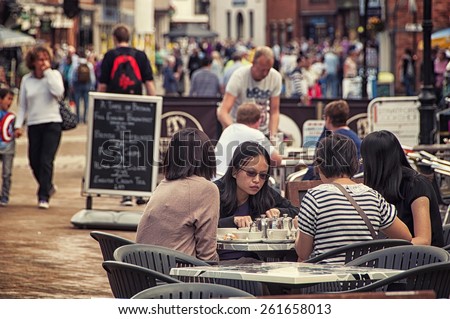 STRATFORD UPON AVON, UK - SEPTEMBER 2, 2014: The main street of very touristic town where playwright and poet William Shakespeare was born. Tourists sitting at the local cafe