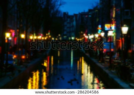 Blurred travel backgrounds. Night view of Red - light district in Amsterdam, Netherlands, where is a concentration of sex shops, strip clubs, adult theaters, etc