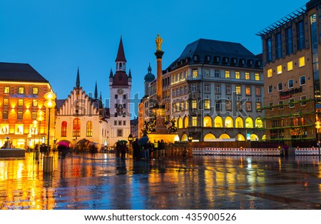 Marienplatz at night in Munich, Germany with old town hall and other buildings - cafes, bars, shops and restaurants. Motion blurred people.