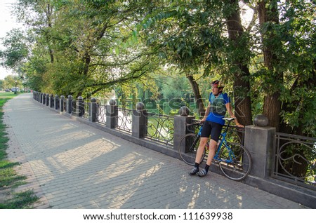 Man  in blue uniform laughs near river with racing bike