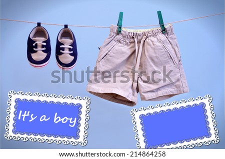A blue card hanging on line with baby booties and shorts isolated on a blue background for you message, It is a Boy Announcement