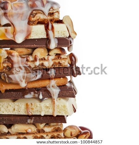 Chocolate and caramel syrup poured on stack of chocolate pieces on white background