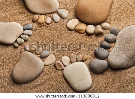 Fun trace feet family of a pebble stone on the sea sand backdrop