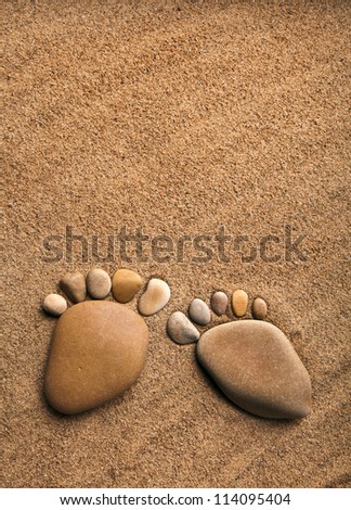 pair trace feet made of a pebble stone on the sea sand desert texture surface backdrop with copy space
