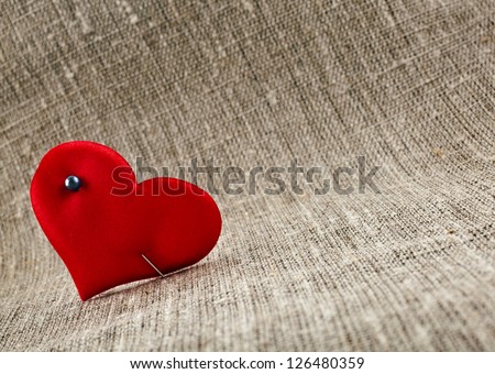 Valentine\'s day card with red heart symbol with needle on fabric sack texture background