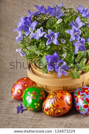 border card , blue flowers in basket with colorful easter egg on canvas sack texture background
