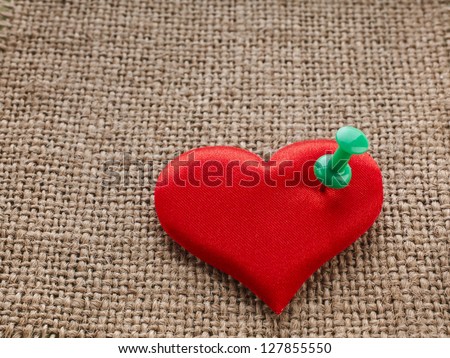 Valentine\'s day red heart symbol with needle on fabric sack texture background