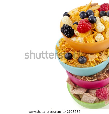 Border of corn flakes in colorful plastic bowl with fresh berries isolated on white background