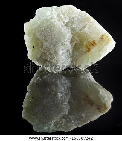 Aquamarine in rock stone with reflection on black surface background