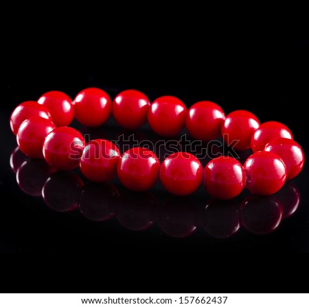 beads of red coral with reflection on black surface background