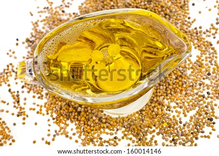 Mustard Oil in gravy boat and heap seeds  isolated on white background