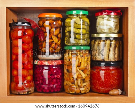 many glass bottles with preserved food in wooden storage