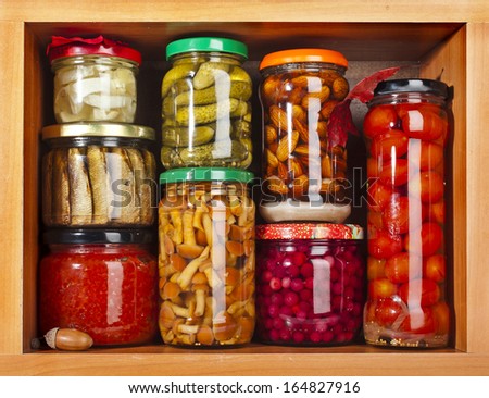 many glass bottles stack with preserved food in wooden cabinet