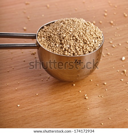 Dry yeast heap in metal scoop on wooden board table
