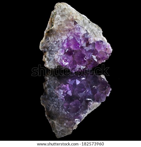 Raw amethyst rock with reflection on black surface background
