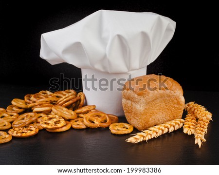 Wheat Ears,  Bread and  Chef Hat on black table background