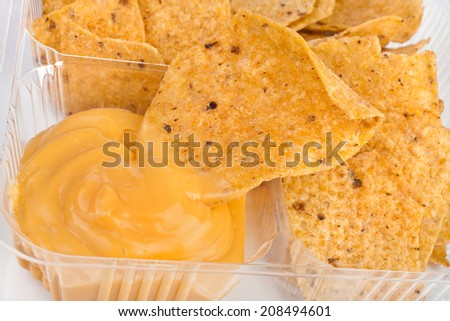 tortilla nachos chips with cheese sauce in plastic container on white background