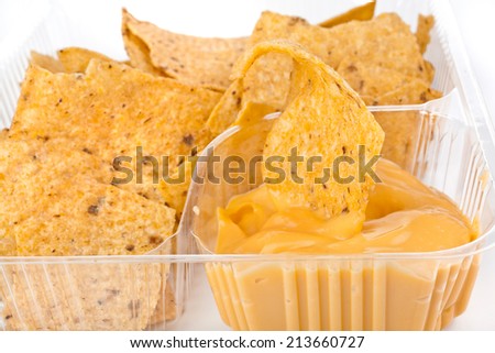 nachos chips with cheese sauce in plastic container isolated on white background