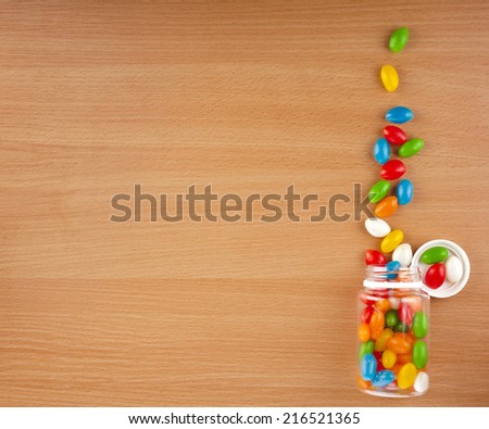 Colored Pills spilled from a bottle  on surface wooden table. top view