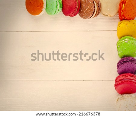 Border Frame of Colorful macaroons, delicious French pastries, stacked on table. Top View.