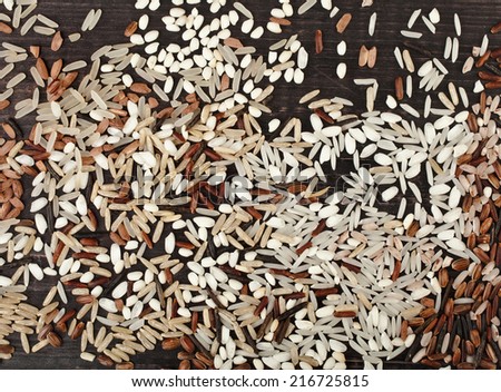 colorful blend of several varieties of whole grain rice in a rustic wooden surface top view background