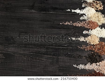 Border of colorful varieties whole grain rice in a rustic wooden surface background