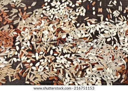 colorful blend of several varieties of whole grain rice in a rustic wooden surface background