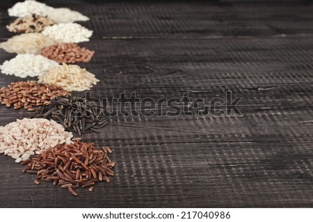 Frame made of several varieties whole grain rice heap in a rustic wooden surface background